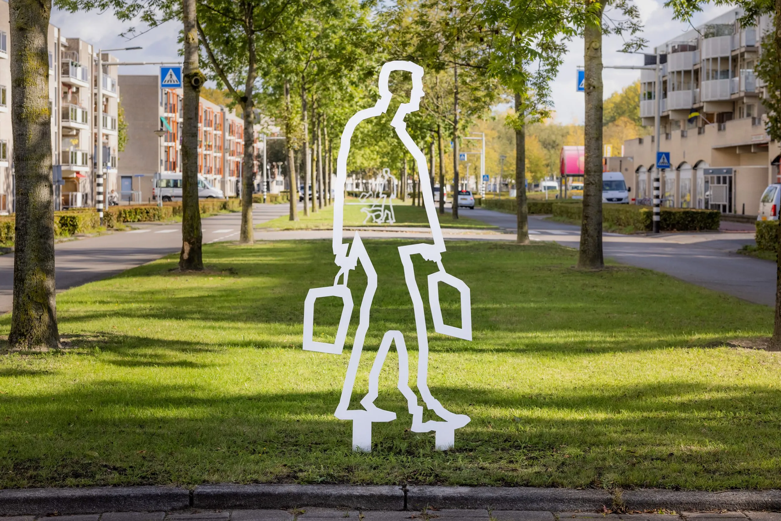 Wit stalen figuur met twee boodschappentassen in de berm