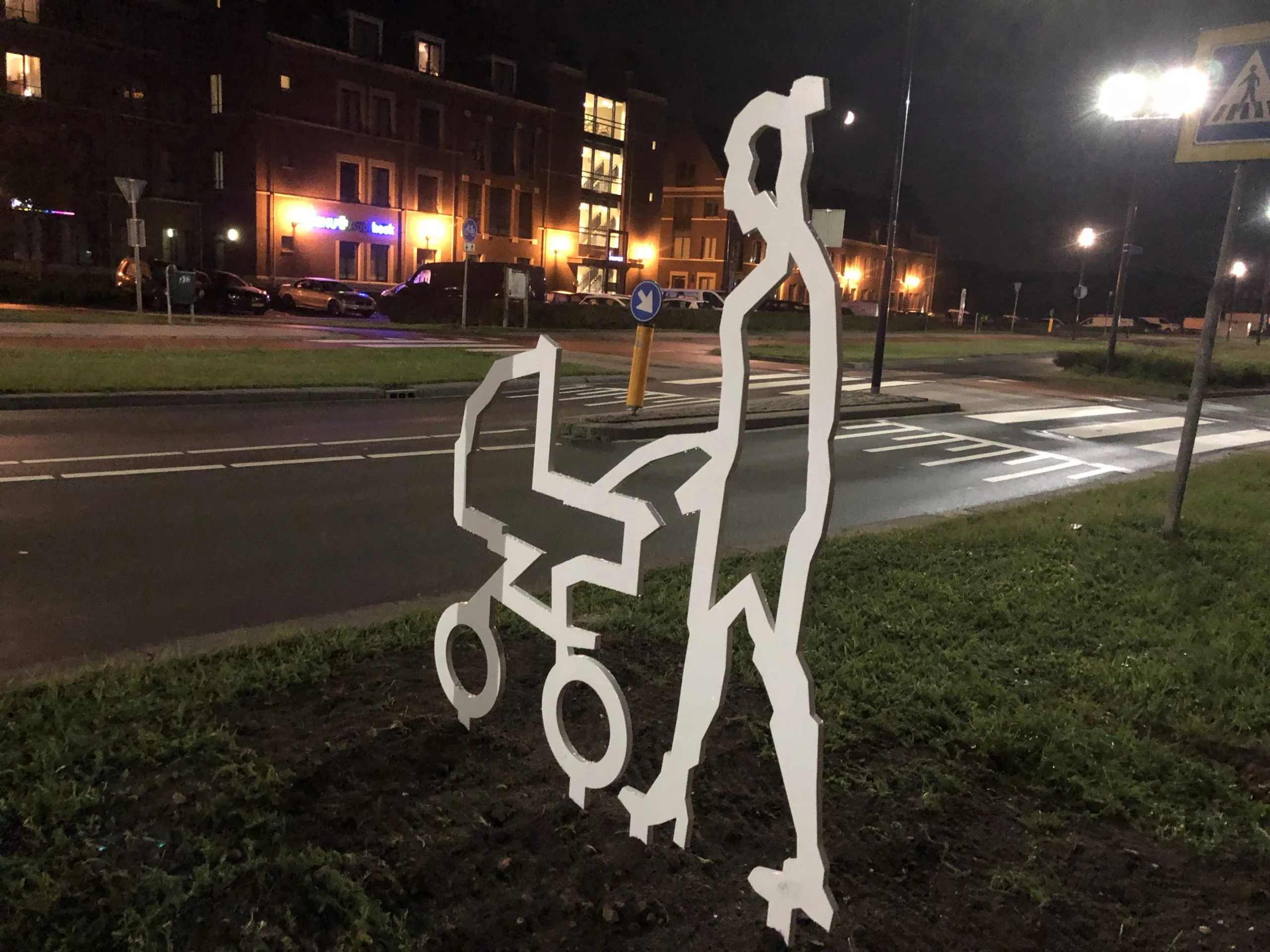 Wit stalen figuur naast de oversteek aan de Stationsweg in Geertruidenberg bij avond