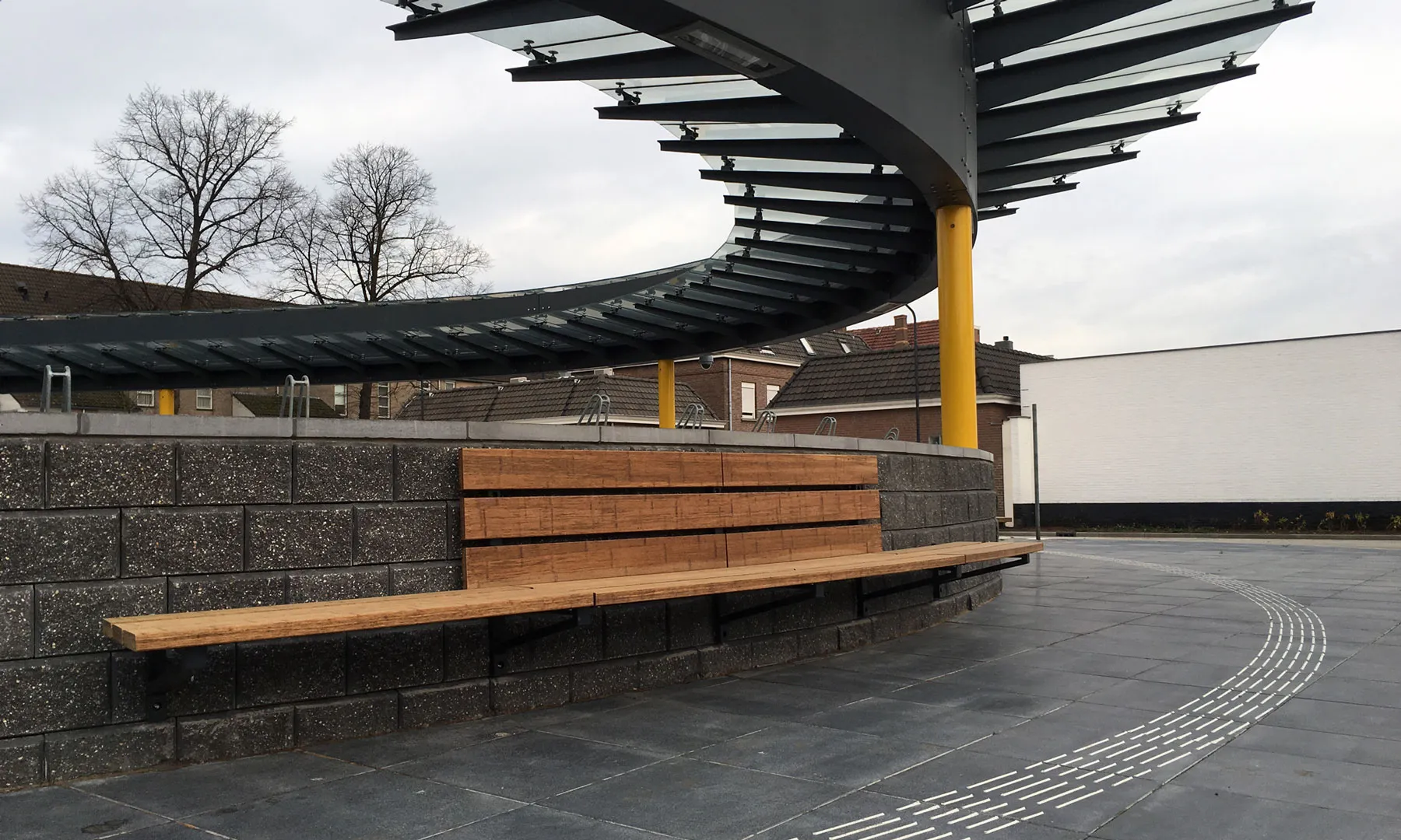 Lange houten bank onder een stalen overkapping bij het busstation in Oosterhout